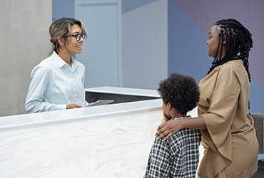 Mother and child standing at dental office front desk