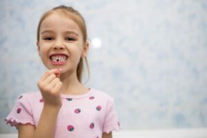 Happy young girl holding her extracted tooth