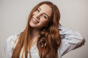 Teen with braces smiling on an off-white background