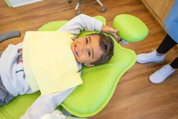 Child smiling in dental chair at Hi Five Kids Dental